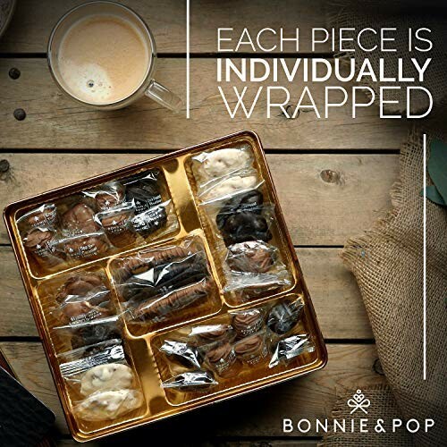 Assorted individually wrapped chocolates and cookies in a gift box with a cup of coffee.