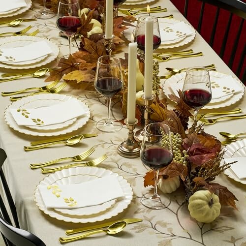 Elegant fall-themed table setting with candles, wine glasses, and autumn leaves.