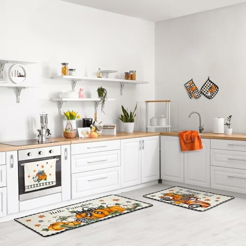 White kitchen with fall-themed rugs and decor featuring pumpkins.